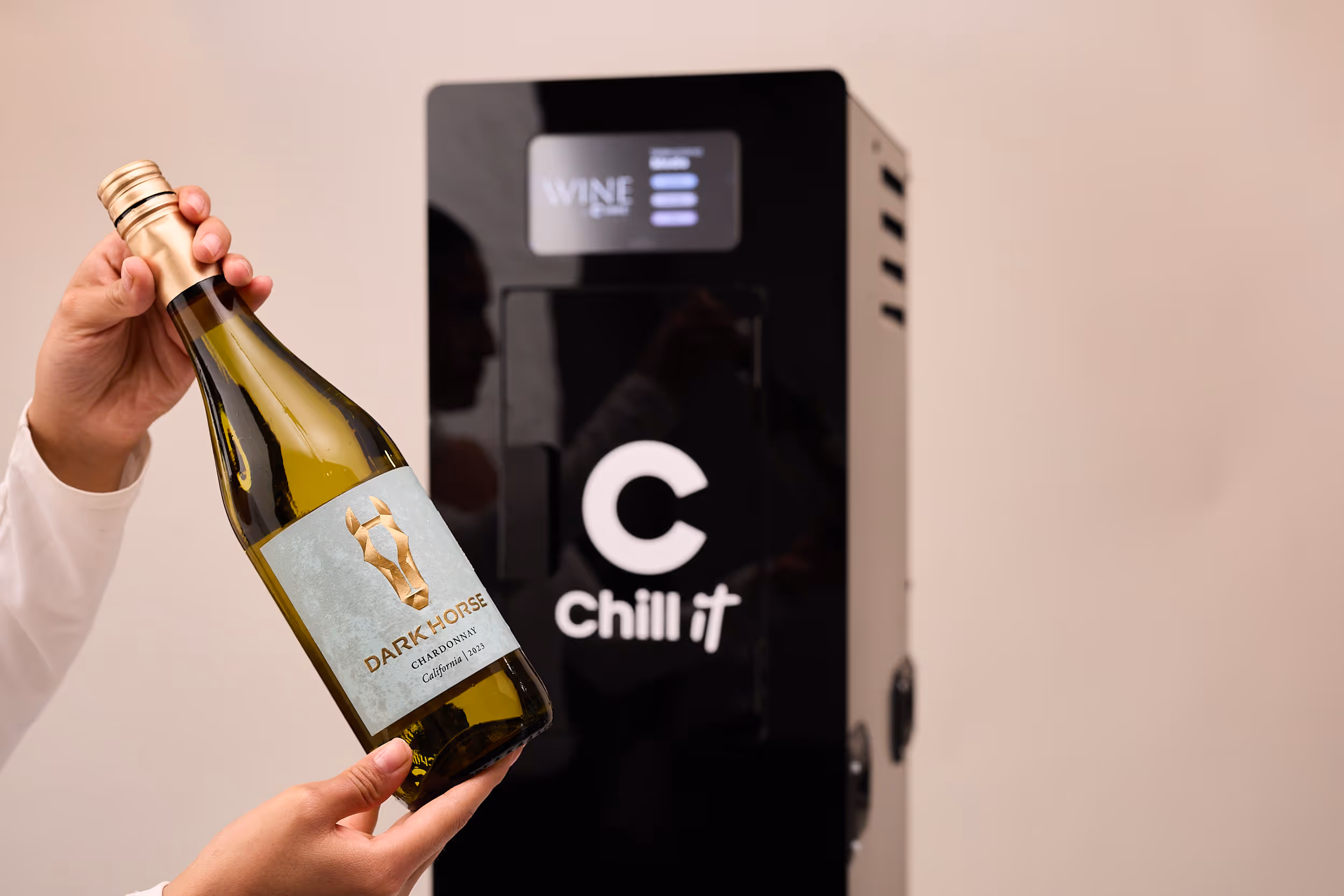 Una botella de vino blanco recién sacada del enfriador CHILL IT WINE, sostenida con las dos manos